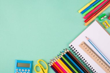 Okul konseptine geri dönelim. Tepede telif alanı olan turkuaz arka planda izole edilmiş renkli okul kırtasiyesinin yukarıdaki görünümü fotoğrafı