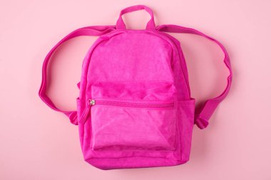 Üstünde pembe arka planda izole edilmiş pembe sırt çantasının resmi var.