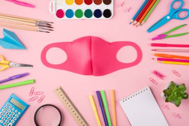 Sosyal uzaklık kavramı. Üst tepede renkli kırtasiye pembe maskesinin resmi ve pastel pembe arka planda izole edilmiş sulu.