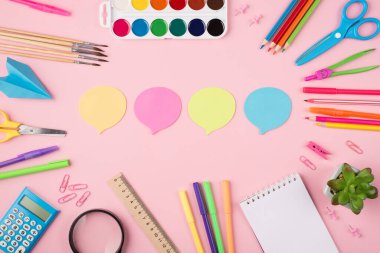 Okul ve iş konseptinde düşünceleri ve fikirleri vurgulamak. İletişim konsepti. Üst tepede renkli kağıt bulutların ve pastel pembe arka planda izole edilmiş sulu kırtasiyelerin fotoğrafı var.