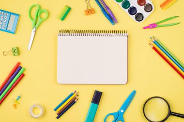 Tepede boş defter resimli, telif boşluğu olan sarı arkaplanda izole edilmiş renkli kırtasiye.