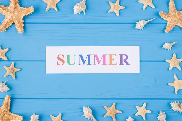 暑假的概念 顶部俯瞰图片的单词夏天 海贝壳和海鱼孤立在蓝色的木制背景 — 图库照片