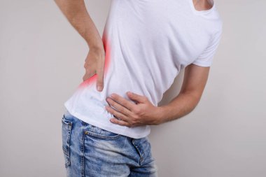 Yan profil. Mutsuz üzgün üzgün adamın stüdyo fotoğrafı. Düşük vücut parçasına dokunan, arka plandaki gri fotokopi alanına el izole edilmiş üzgün adam.