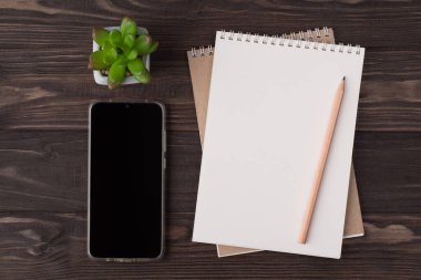 Yukarının üstünde boş bir defter, ahşap bir telefon ve ahşap arka planda izole edilmiş sulu bir kalem resmi duruyordu.