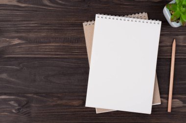 Tepedeki düz görünümde boş bir defter telefonunun ve sağ tarafa yerleştirilmiş sulu bir fotoğrafın telif alanı ile izole edilmiş ahşap zemin üzerinde yatıyordu.