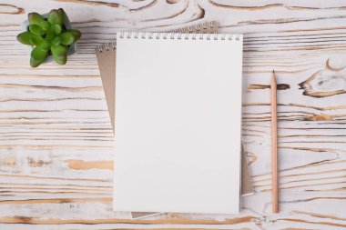 Tepedeki düz görünümde boş bir defterin fotoğrafı bulunuyordu. Lezzetli ve ahşap kalemle birlikte, aydınlık ahşap arka planda, kopyalanmış bir kalem.