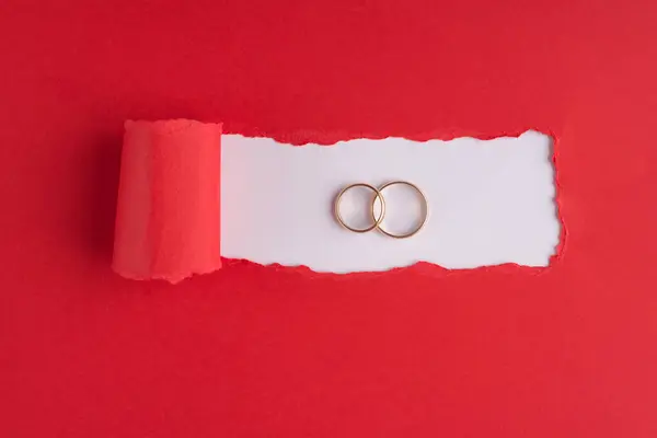 婚姻概念 顶部上方的图片 两个不同大小的戒指在撕破的红纸上 白色背景 有彩色空间 — 图库照片