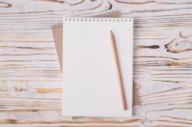 Tepedeki düz görünümde boş bir defter ve ahşap kalemle izole edilmiş, kopyalanmış tahta zemin üzerinde yatıyordu.