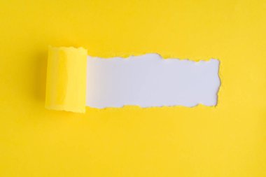 Tepeden bakıldığında, yırtık sarı kağıdın resmi beyaz arkaplanda ve kopyalanmış boşlukta