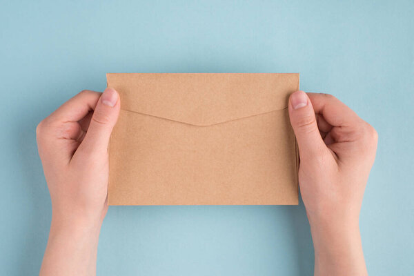 First person people above top overhead close up view photo of female woman hands holding one envelope in hands isolated over pastel color blue background