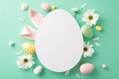 Paskalya projesi düzeni: Çeşitli yumurtaların üst görünümü, sevimli tavşan kulakları, ve deniz yeşili bir üste papatya çiçekleri, notlar veya pazarlama için yumurta şeklinde boş bir çerçeve.