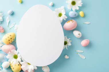 Paskalya rüyası gösterisi. Kaleydoskop yumurtalarının üst görüntüsü ve açık mavi bir yüzey üzerinde sevimli mesajlar veya reklamlar için oval açık olan yumuşak papatyalar.