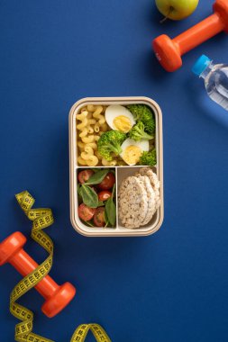 Dikey sağlıklı gıda öğeleri içeren yemek hazırlama halterleri, halterler ve bant gibi temel sağlık malzemeleriyle çevrili.