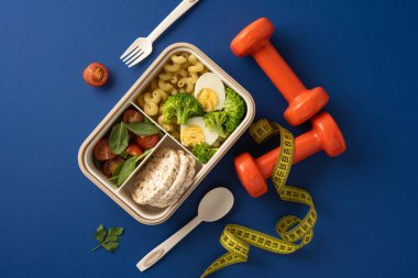 Sebze, makarna ve pirinç keklerinin yanı sıra halterler ve mezura ile besleyici bir bento kutusu, sağlık ve zindeliği teşvik eder.