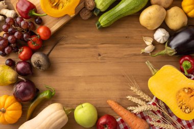 Tahta bir masanın üzerinde çeşitli meyve ve sebzelerin rengarenk düzenlenmesi, doğal ve şenlikli sunumlarıyla hasatın ve Şükran Günü 'nün ruhunu çağrıştırıyor.