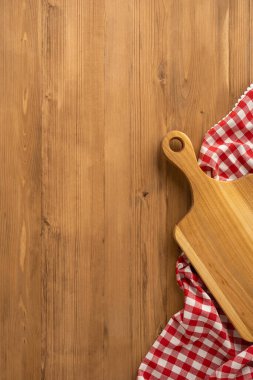 Kesme tahtası ve kırmızı kareli masa örtüsünü gösteren tahta tezgahın dikey görüntüsü. Şükran Günü kutlaması ve hasat ile ilişkilendirildi