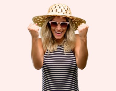 Büyük başarı, güç, enerji ve olumlu duygular ifade yaz şapka mutlu ve heyecanlı kutluyor zafer giyen güneş gözlüğü kullanan genç kadın. Yeni iş neşeli kutluyor