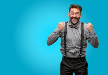 Orta yaş adam, sakal ve papyon mutlu ve heyecanlı kazanan jest ifade. Başarılı ve zafer, zafer kutluyor