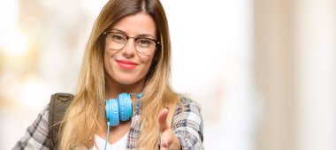 Genç öğrenci kadın sırt çantası ve kulaklık ile el sıkışma poz karşılama, güven ve başarı kavramı ifade, tebrik ellerini tutar