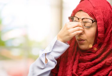 Çok çalışan ve yorgun, rubbes burun yorgunluk nedeniyle uykulu ifade ile hijab giyen genç Arap kadının