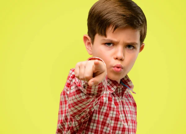 Parmak ile açık sarı arka plan üzerinde işaret eden yeşil gözlü yakışıklı yürümeye başlayan çocuk