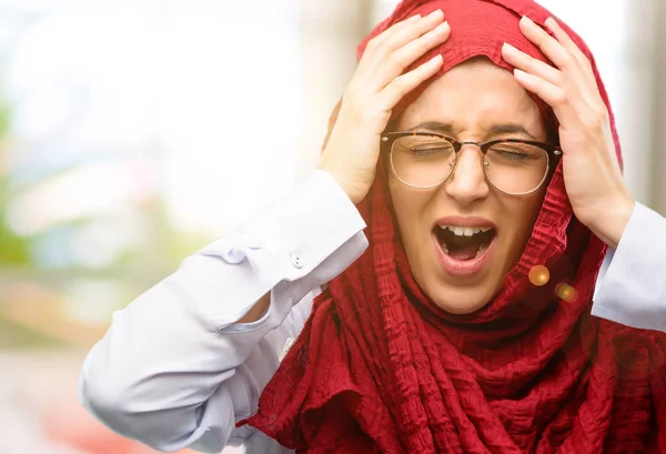 Genç Arap kadın giyiyor hijab stresli tutmak ellerinde kafa, panik, korku içinde bağırarak