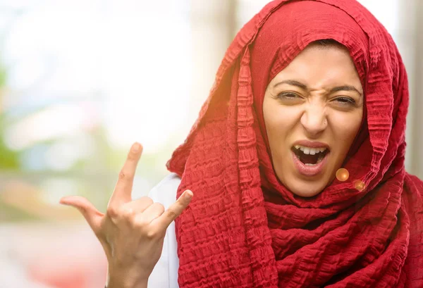 Rock simge elle yapma, bağırarak ve kutlama hijab giyen genç Arap kadın