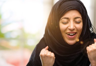 Büyük başarı, güç, enerji ve olumlu duygular ifade hijab mutlu ve heyecanlı kutluyor zafer giyen genç Arap kadın. Yeni iş neşeli kutluyor