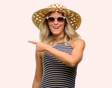 İşaret parmağı ile uzak yan yaz şapka güneş gözlüğü kullanan genç kadın