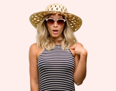 Parmak ile işaret yaz şapka mutlu ve tezahürat ifade wow jest, giyim güneş gözlüğü kullanan genç kadın