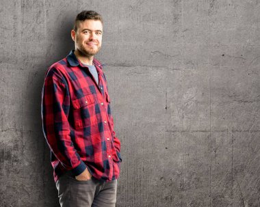 Genç yakışıklı adam kendinden emin ve mutlu kameraya bakarak büyük bir doğal gülümseme ile