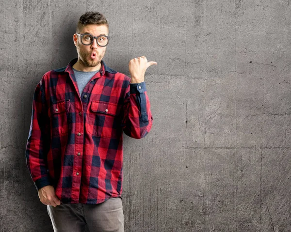 Young handsome man happy and surprised cheering expressing wow gesture pointing up