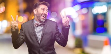 Orta yaş adam, sakal ve papyon mutlu ve heyecanlı kazanan jest ifade. Başarılı ve zafer, gece kulübünde muzaffer kutluyor