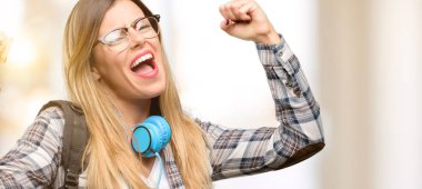 Genç öğrenci ve kadın ile kulaklık sırt çantası mutlu ve heyecanlı büyük başarı, güç, enerji ve olumlu duygular ifade zaferini kutluyor. Yeni iş neşeli kutluyor