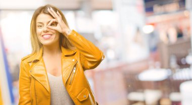 Güzel genç kadın parmakları Tamam jest olarak kameradan bakıyorsun. Taklit dürbün, güzel gözleri ve gülümseme Restoran