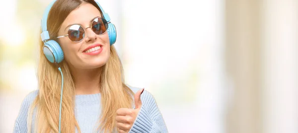 Mujer Joven Escuchar Música Con Auriculares Sonriendo Ampliamente Mostrando Pulgares —  Fotos de Stock