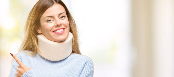 Young injured woman wearing neck brace collar pointing away side with finger