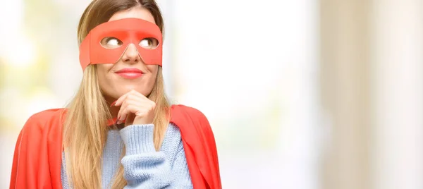 Young super woman thinking and looking up expressing doubt and wonder