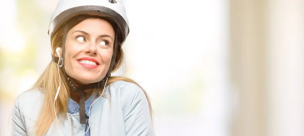 Young woman with bike helmet and earphones thinking and looking up expressing doubt and wonder