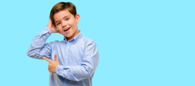 Mavi arka plan üzerinde uzak yan parmak ile işaret yeşil gözlü yakışıklı yürümeye başlayan çocuk