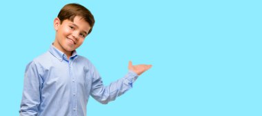 Bir şey üzerinde mavi arka plan boş elinde tutan yeşil gözlü yakışıklı yürümeye başlayan çocuk