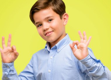 Meditasyon ve gevşeme sarı arka plan üzerinde ifade iki eliyle ok işareti jest yapıyor yeşil gözlü yakışıklı yürümeye başlayan çocuk