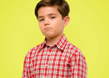 Kendinden emin ve mutlu bir büyük doğal yeşil gözlü yakışıklı yürümeye başlayan çocuk gülümseme kameraya sarı arka plan üzerinde seyir