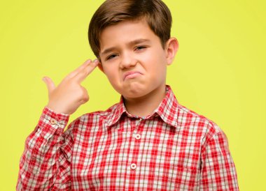 Mutsuz yeşil gözlü yakışıklı yürümeye başlayan çocuk intihar jest yapmak her şeyi yorgun. Sürgünler silah, sarı arka plan üzerinde üzgün taklit el ile