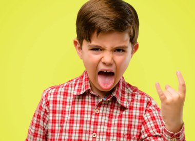 Rock simge elle yapma, bağırarak ve dilini çıkarmış sarı arka plan üzerinde kutluyor yeşil gözlü yakışıklı yürümeye başlayan çocuk