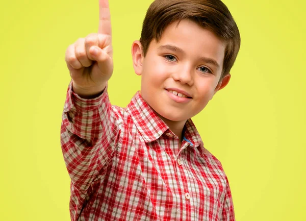 英俊的蹒跚学步的孩子与绿色的眼睛举起手指 是数字一在黄色背景 — 图库照片