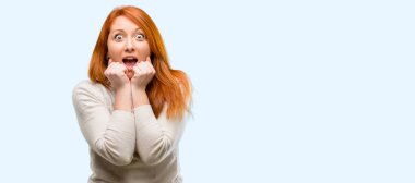 Güzel genç Kızıl saçlı kadın mutlu ve ifade wow jest tezahürat üzerinde mavi arka plan izole