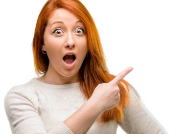 Uzak yan beyaz arka plan üzerinde izole parmak ile işaret eden güzel genç Kızıl saçlı kadın