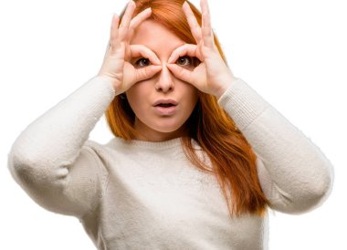 Güzel genç Kızıl saçlı kadın parmakları Tamam jest olarak kameradan bakıyorsun. Beyaz arka plan üzerinde izole dürbün taklit