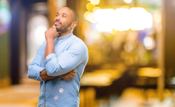 Африканский американец с бородой думает и смотрит вверх, выражая сомнение и удивление ночью
